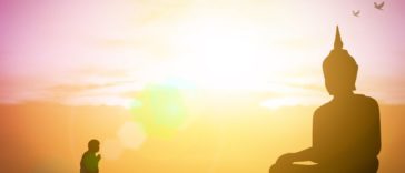 man at Buddha statue wondering what karma means