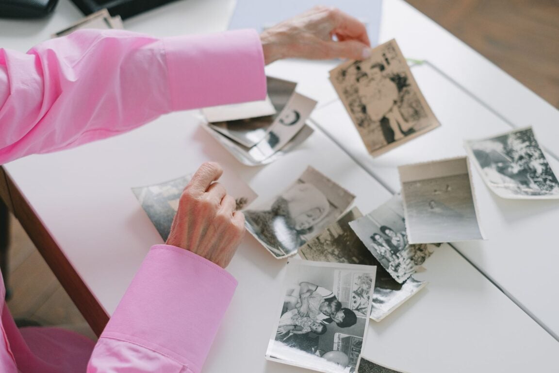 An older woman sorting through old black-and-white family photographs