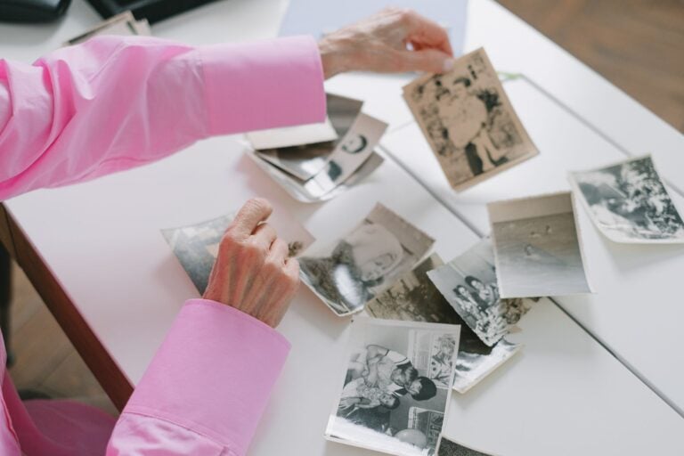 An older woman sorting through old black-and-white family photographs