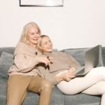 Adult daughter relaxing on a couch with her mother at home
