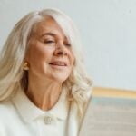 Woman with long gray hair absorbed in reading a book at home