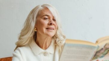 Woman with long gray hair absorbed in reading a book at home